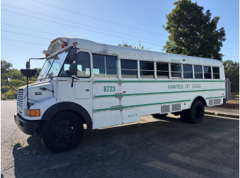 Photograph of a light-blue school activity bus parked outdoors.